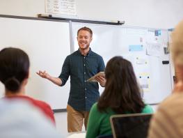 A male teacher standing in front of adult learner 