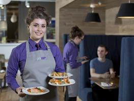 Hospitality student serving plates of food in our training restaurant Scholars' 