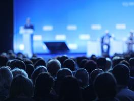 a view from behind of an audience at a conference 