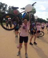 Kerry Bamber raising her bike above her head at finishing line of cycle challenge in Cambodia 