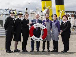 Principal and students from hospitality and nautical on board the TS Queen Mary holding a red and white life ring. 