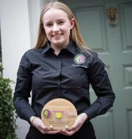 Photo of Tara Humphrey holding her Toque d'Or Front of House winning plaque. 