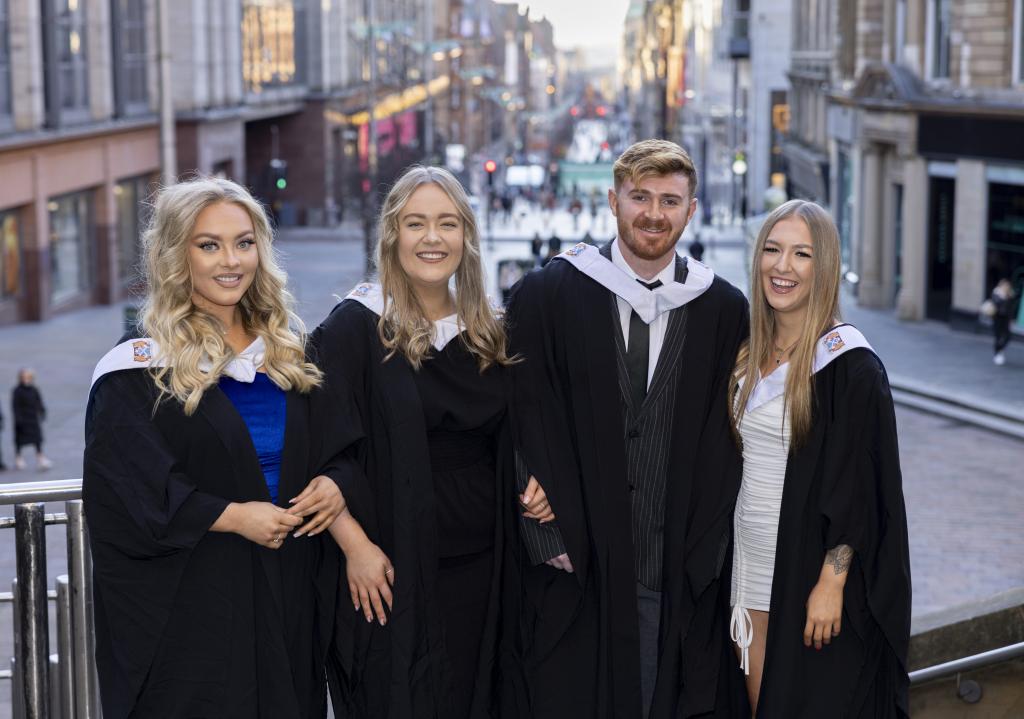Four students standing on the steps at the Concert Hall with Buchanan Street in the background.