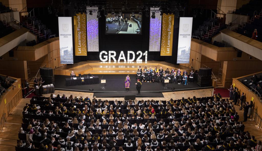 A view of the stage and seating areas filled with graduates taken from above.