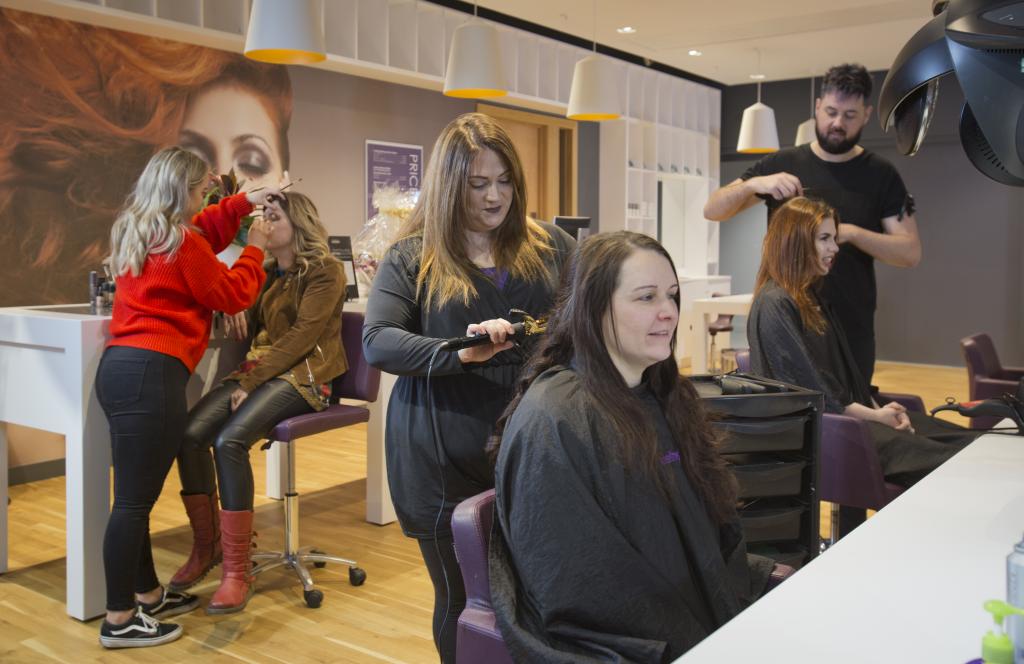 Hairdressers working on a clients hair in a salon.