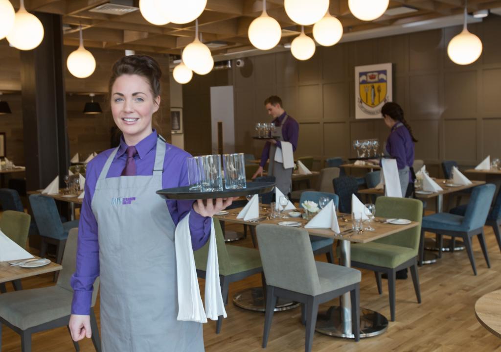 Student serving drinks in Scholars Training Restaurant.