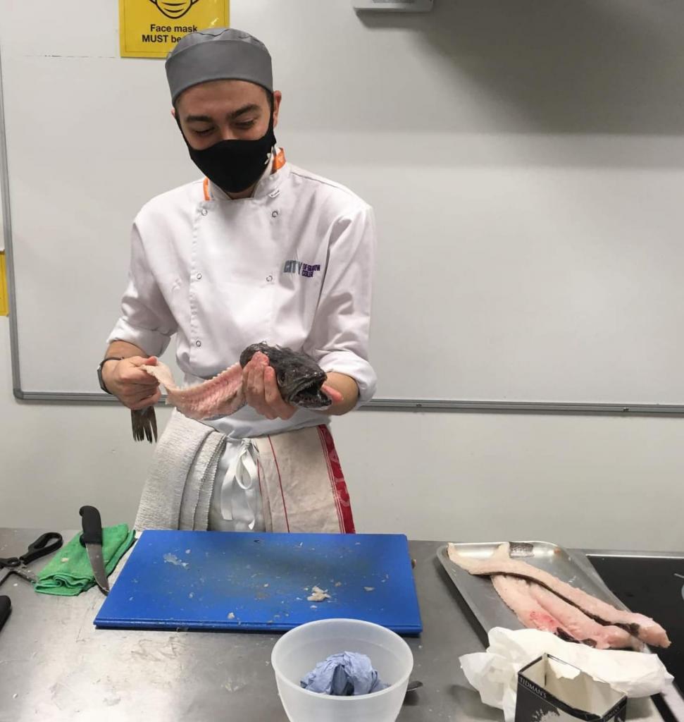 Photo of Robbie McDougall filleting a fish in the college kitchens
