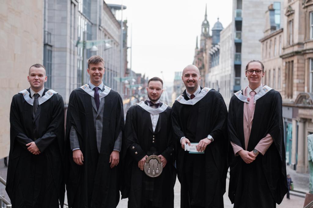 A group of students in graduation gowns outside the Royal Concert Hall.