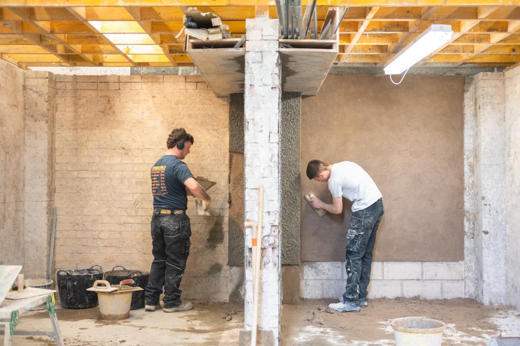 Two plastering students working in construction workshop