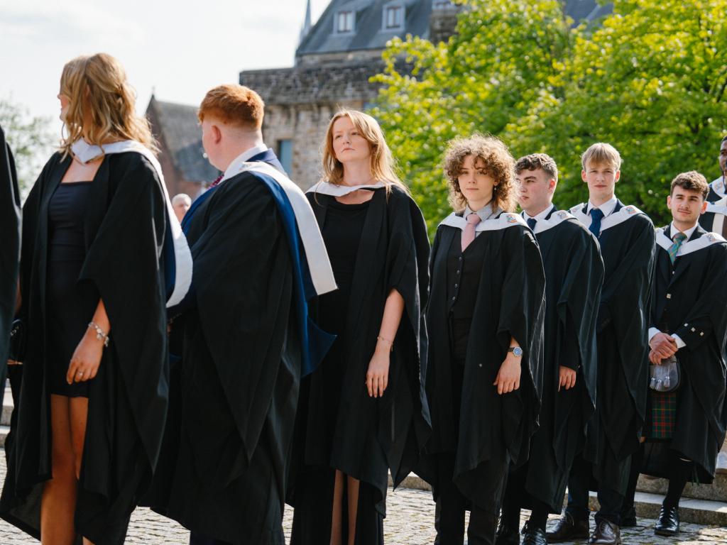 Students in academic gowns lining up outside Glasgow Cathedral