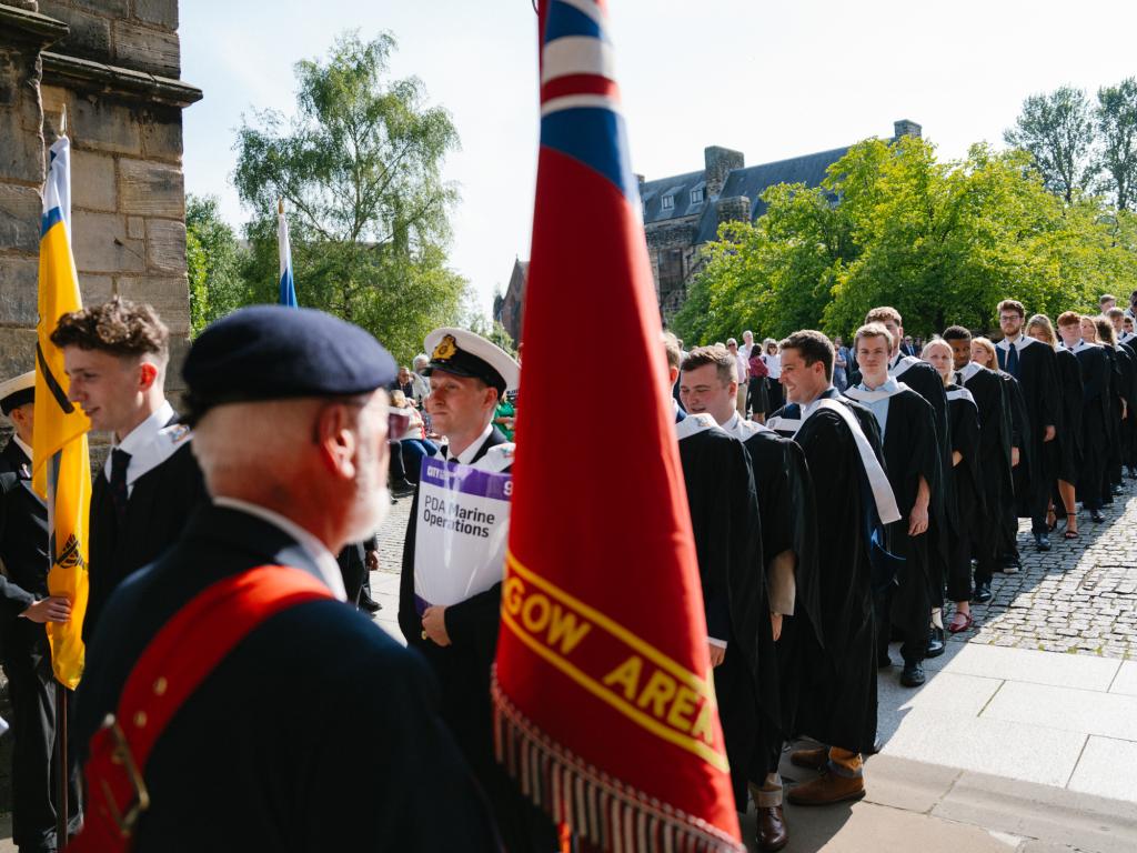 Students in academic gowns lining up outside Glasgow Cathedral