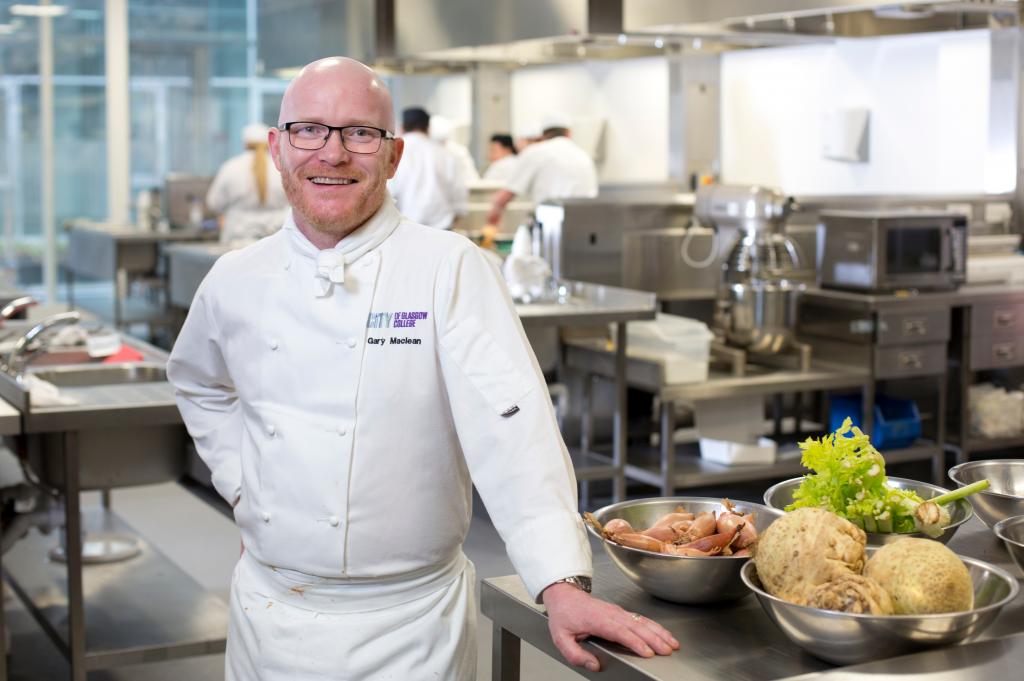 Gary Maclean standing in college kitchen next to counter loaded with vegetables