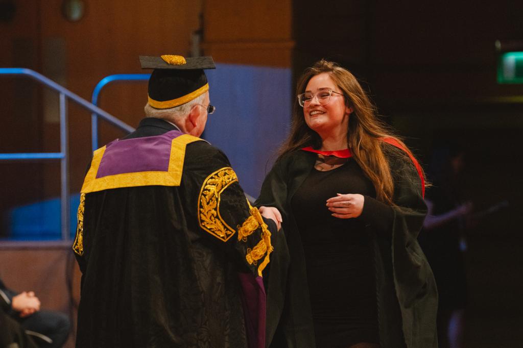 Principal on stage with a graduate