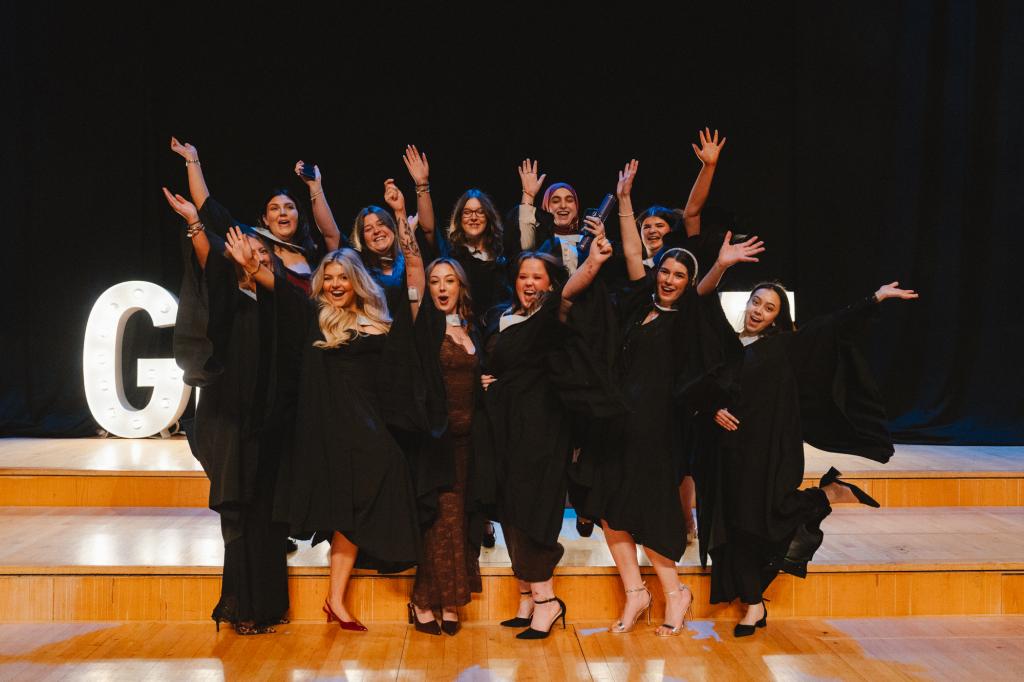 A group of students on stage celebrating graduation