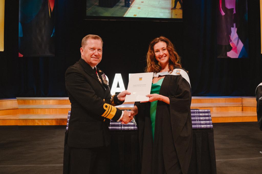 A student on stage with their certificate and guest speaker
