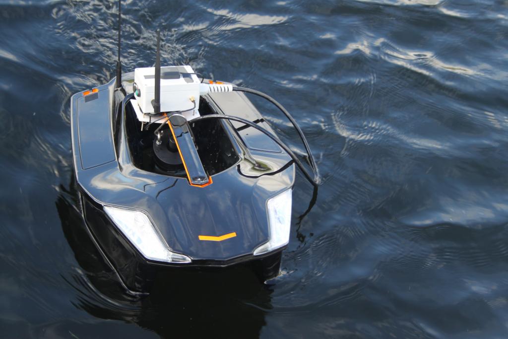 Aquabot, a water quality monitoring platform using digital sensor technology - looks like a small black boat on the water