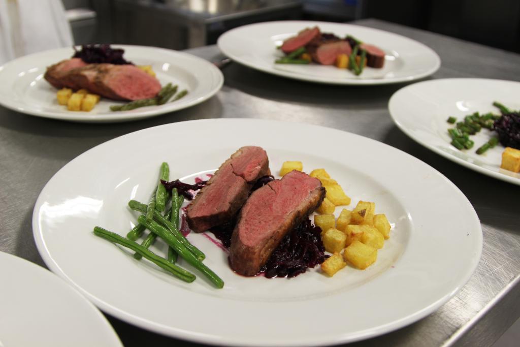 Four plates of food with slices of beef, vegetable and potatoes prepared by our Professional Cookery students.
