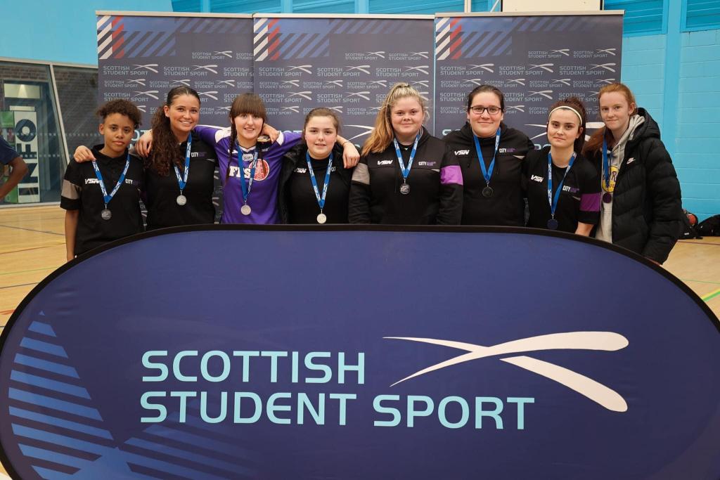 Womens football team lined up with medals on.