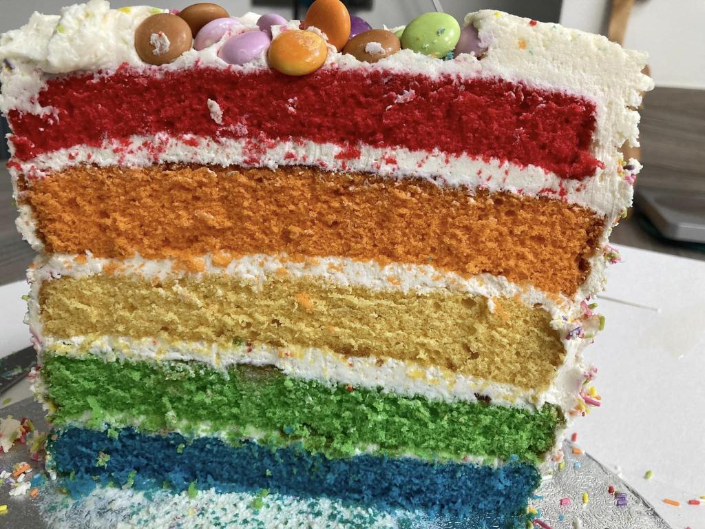 City Market rainbow cake with multi coloured layers and icing.