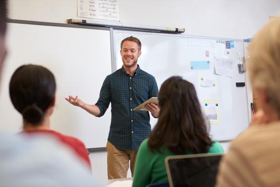 A male teacher standing in front of adult learner