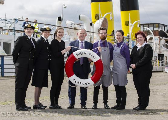 Principal and students from hospitality and nautical on board the TS Queen Mary holding a red and white life ring.