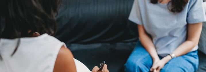 Two people sitting on a couch facing each other.