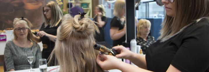 Hairdresser cutting hair in front of mirror