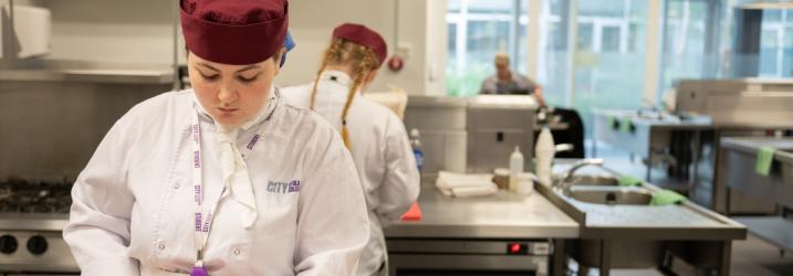 Two students in chefs whites working in a professional kitchen at the college.