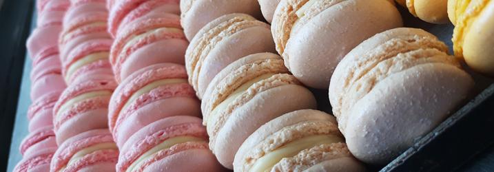 Rows of macarons in different colours pink, white and yellow