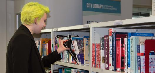 Student browsing books in Library at City campus.