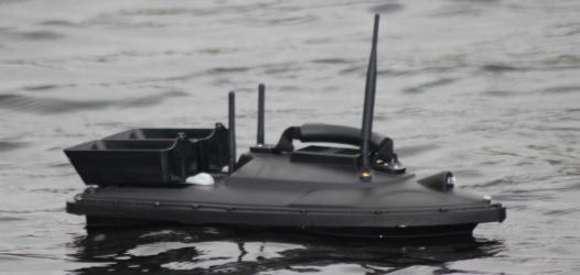 Aquabot, a water quality monitoring platform using digital sensor technology - looks like a small black boat on the water.