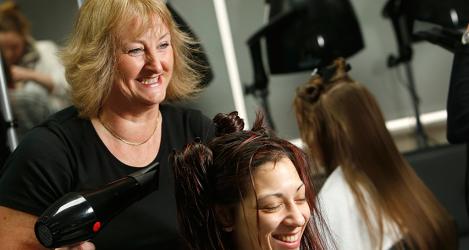 A hairdresser drying a clients long hair in a salon.