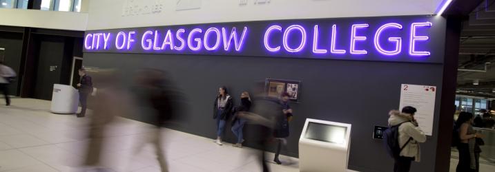 City campus entrance with students walking about and focused on a purple neon sign saying City of Glasgow College.