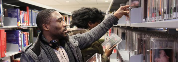 Student taking a book from the library shelf