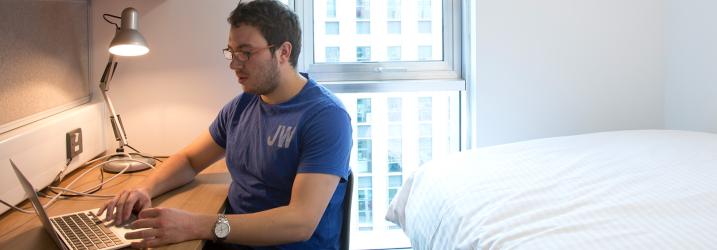 Student studying in a Student's Accommodation room on the Riverside campus