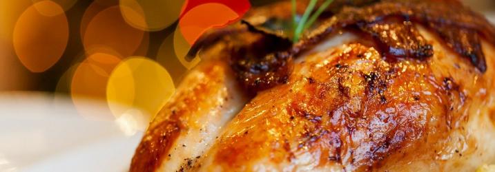 A golden roasted whole turkey surrounded by brussels sprouts and carrots and parsley.
