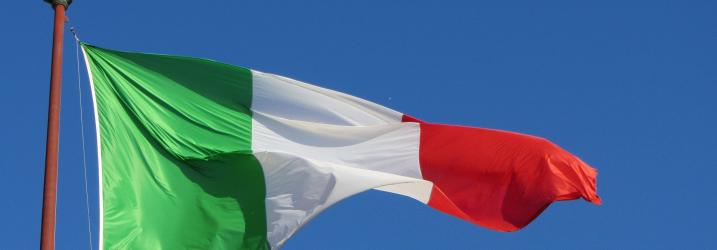 Italian flag blowing in the wind with clear blue sky.