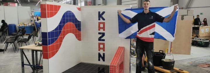 Worldskills tiling student holding saltire in front of his finished display.
