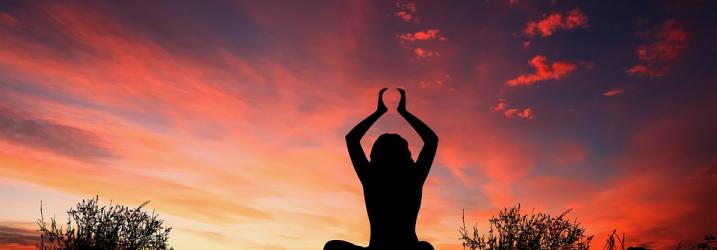 Person performing Yoga outside at sunset