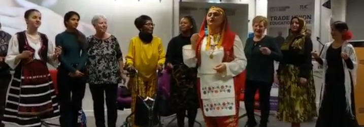 The Joyous Choir, women of different nationalities dressed in colourful national dress standing in a row singing